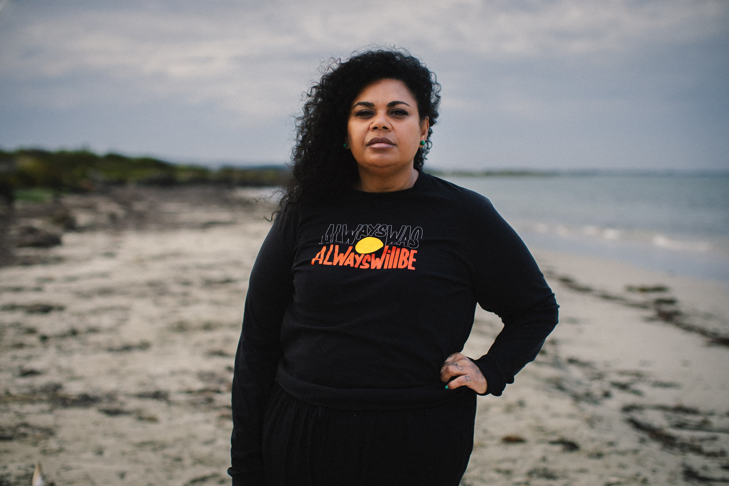 Gunditjmara and Yorta Yorta woman Keicha Day stands on a beach wearing an “Always Was, Always Will Be” jumper.